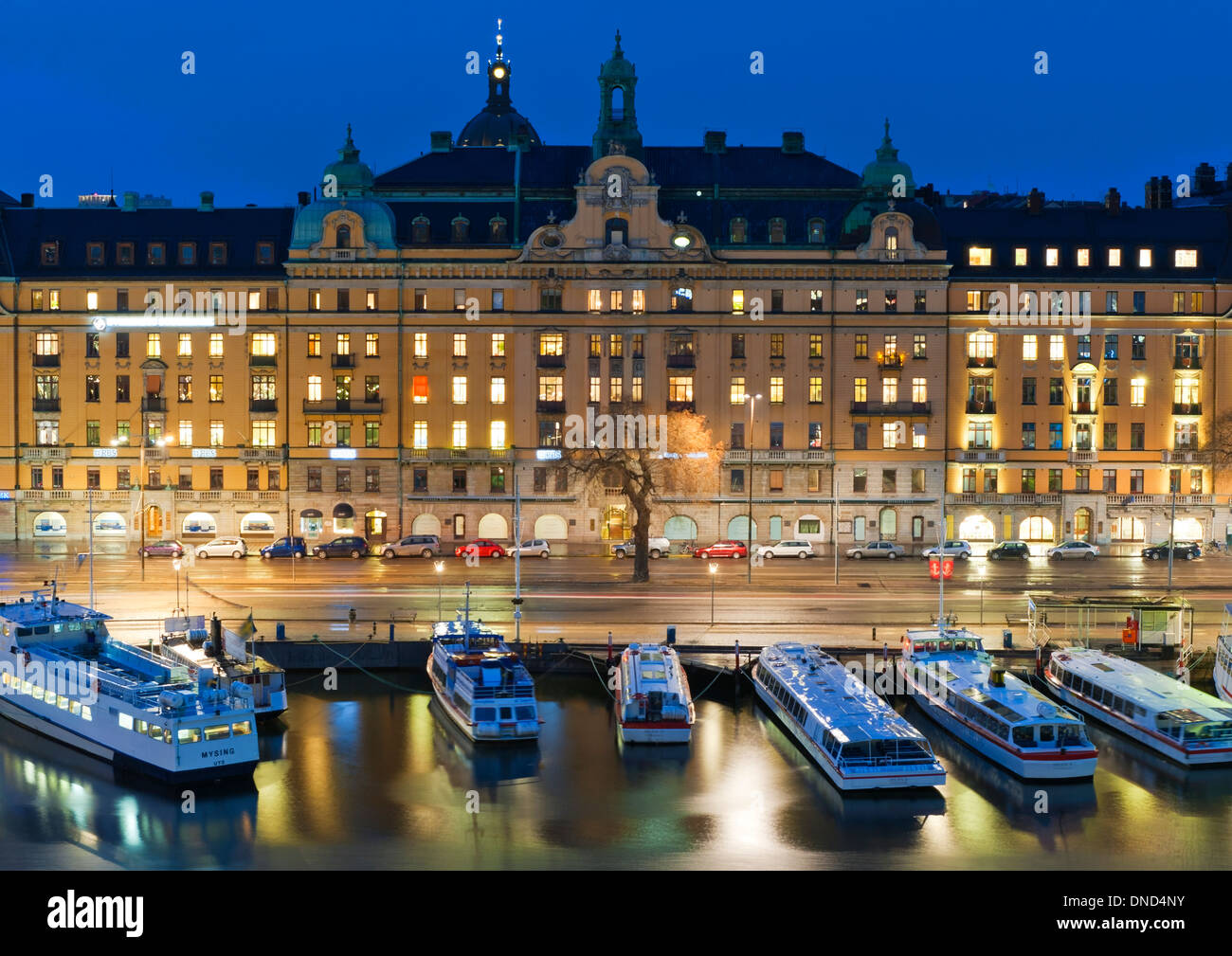 Piccoli traghetti ormeggiati a Nybroviken bay, con l'edificio Art Nouveau, 1-5 Strandvägen (1902-1904) sul boulevard dietro. Foto Stock