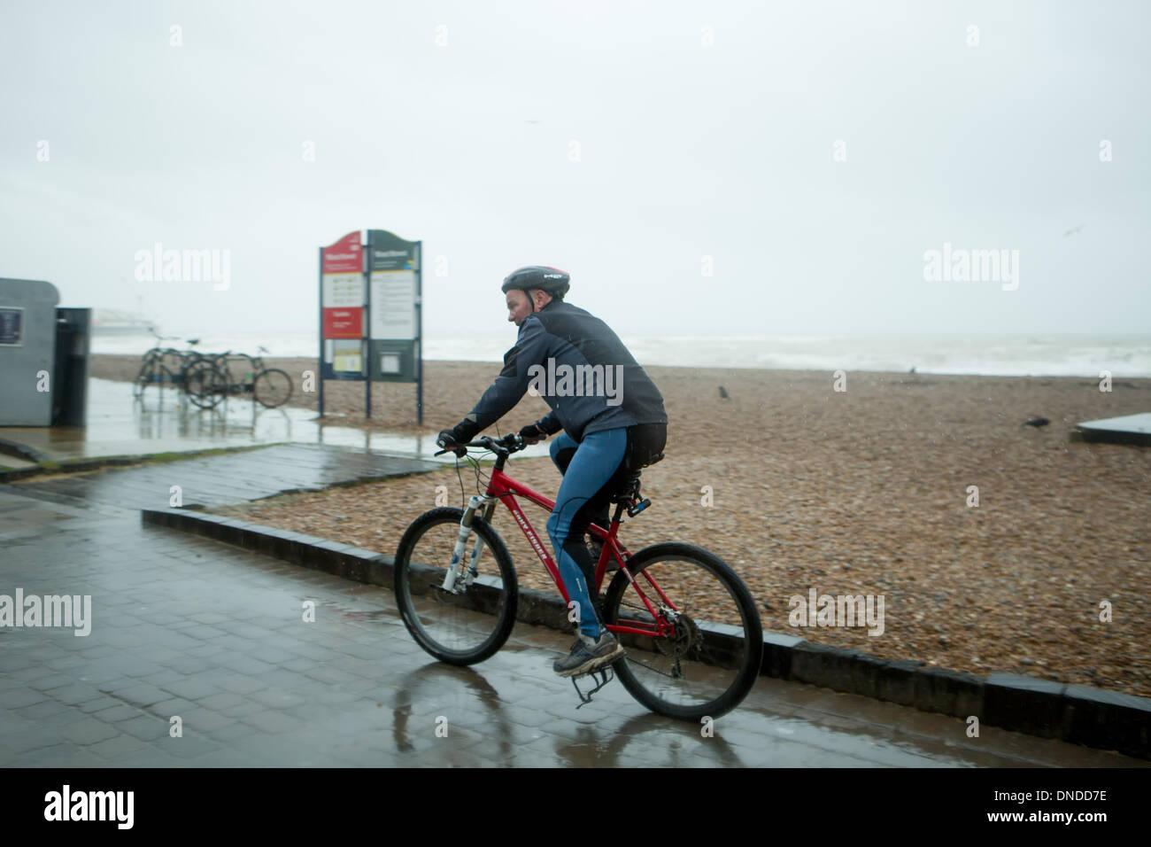 Ciclista combattendo le tempeste condizioni presso la spiaggia di Brighton, Brighton East Sussex Regno Unito il 23 dicembre 2013. Foto Stock