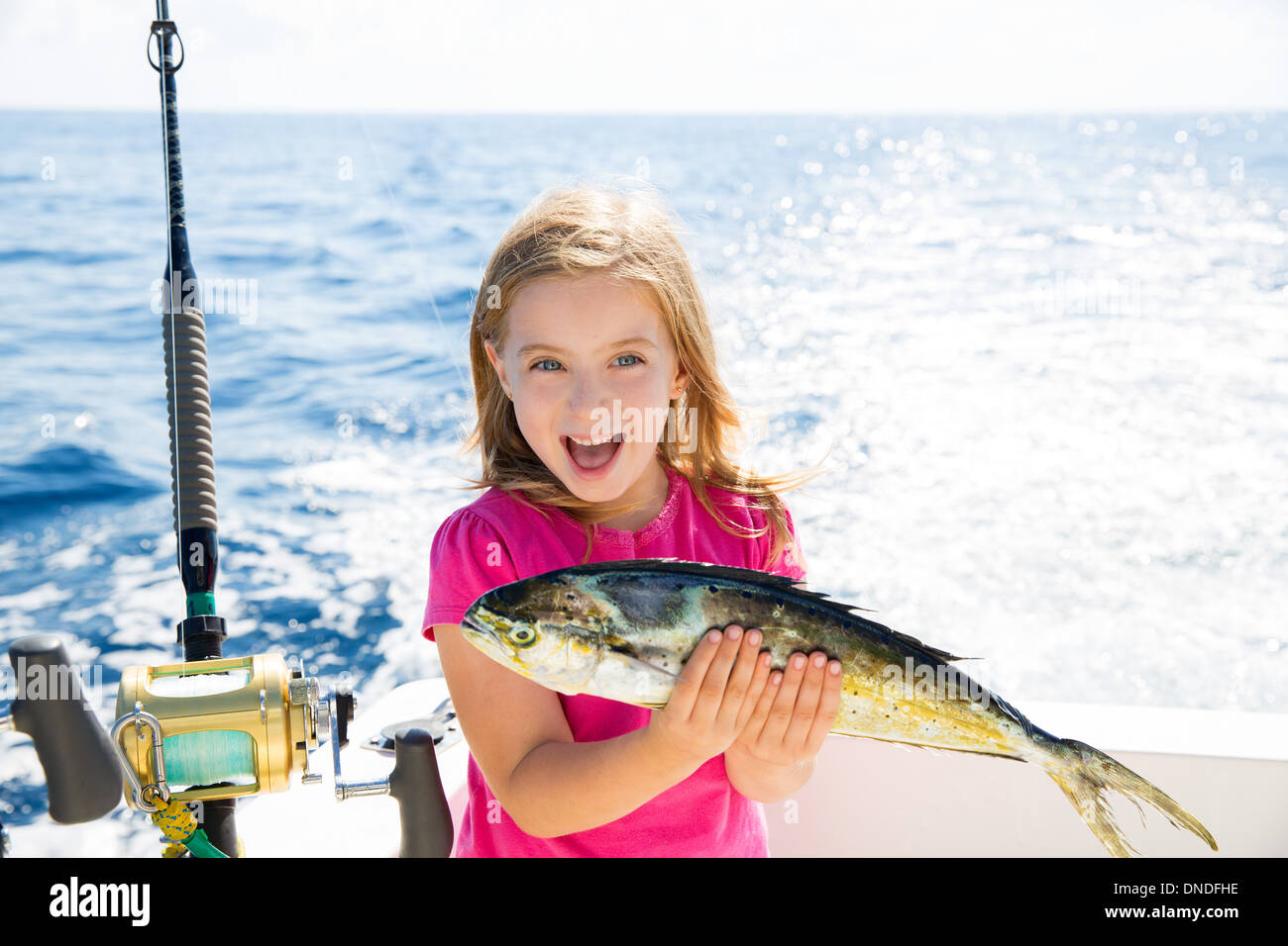 Blonde kid ragazza la pesca Dorado mahi-mahi pesce felice con trolling fermo sulla coperta della barca Foto Stock