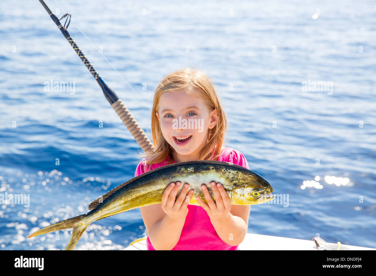 Blonde kid ragazza la pesca Dorado mahi-mahi pesce felice con trolling fermo sulla coperta della barca Foto Stock