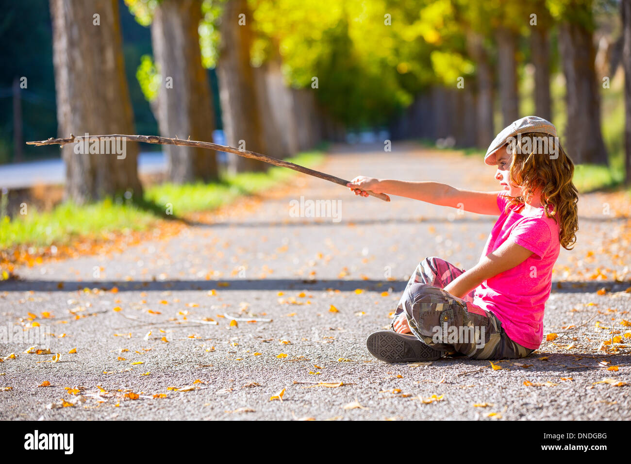 Autunno kid ragazza con Pantalone mimetico con puntamento escursionista stick di diramazione Foto Stock