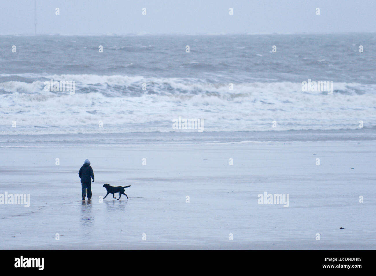 Porthcawl, Regno Unito. Il 23 dicembre 2013. Come la pioggia torrenziale alleggerite-off, la gente ha preso le passeggiate di controventamento in forti venti blustery sul lungo tratto sabbioso a riposo baia vicino Porthcawl. Credito: Graham M. Lawrence/Alamy Live News. Foto Stock