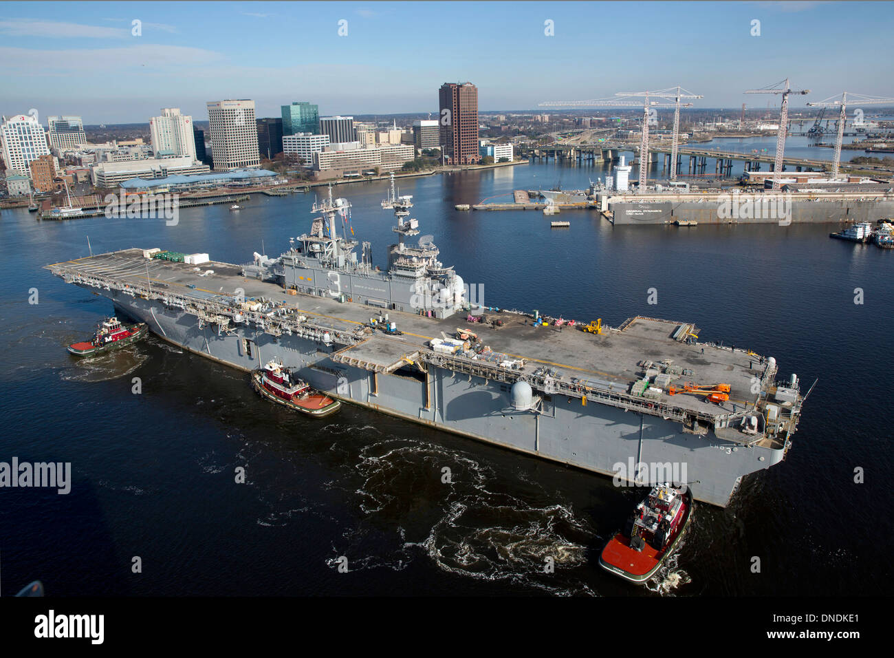 Rimorchiatori posizione la US Navy Amphibious Assault nave USS Kearsarge per immettere BAE Systems Norfolk la riparazione navale per un periodo di cinque mesi di manutenzione pianificata Dicembre 16, 2013 in Norfolk, VA. Foto Stock