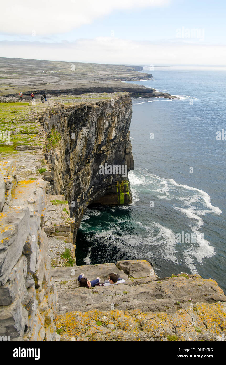 I turisti alla ripida scogliera accanto a Dun Aengus pietra preistorici fort, Inishmore (Inis Mor), Isole Aran Irlanda Foto Stock