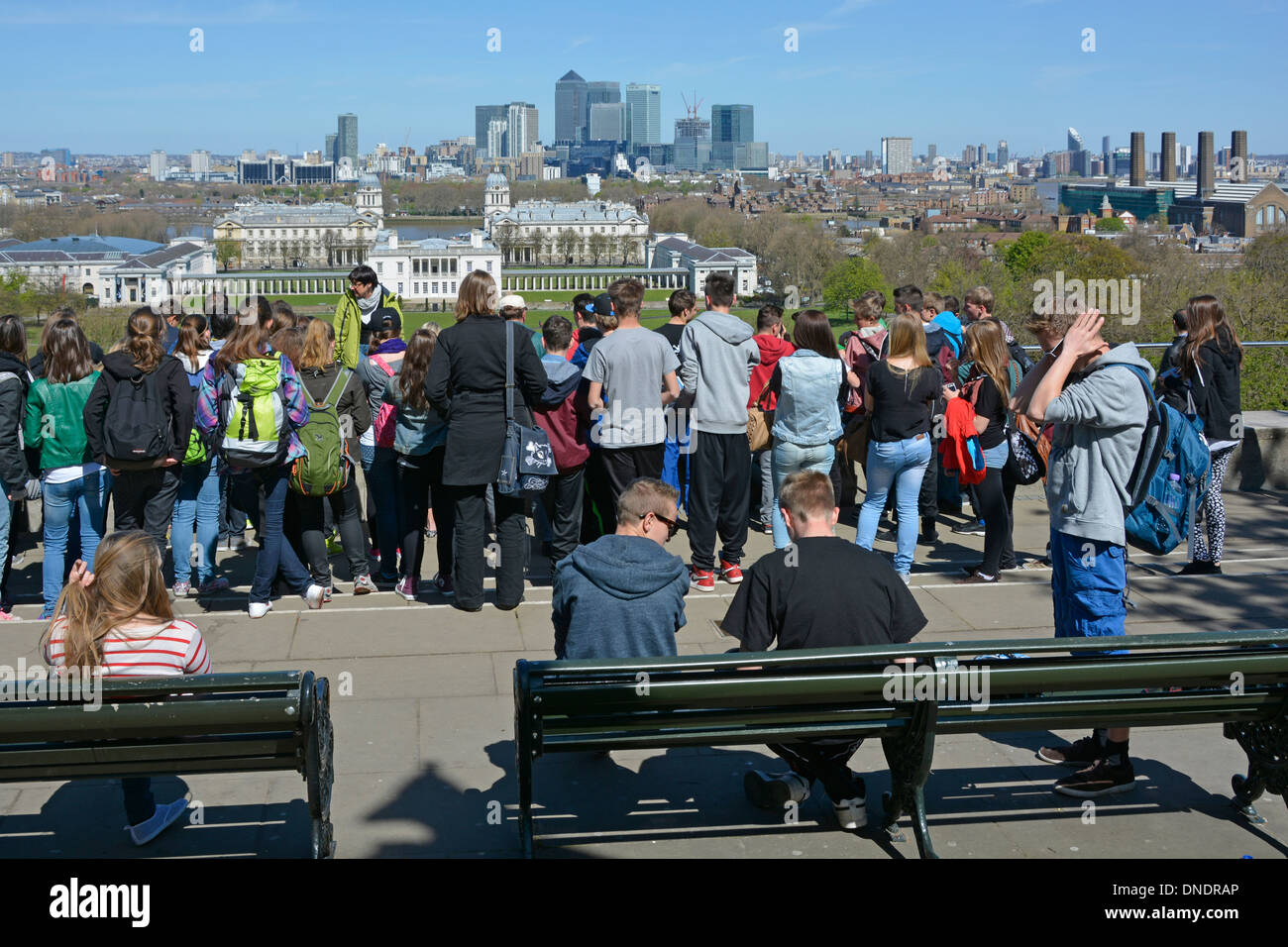Un gruppo di ragazze e ragazzi in visita di istruzione a Greenwich Park & Observatory guardando vista verso Queens House e da Canary Wharf Foto Stock