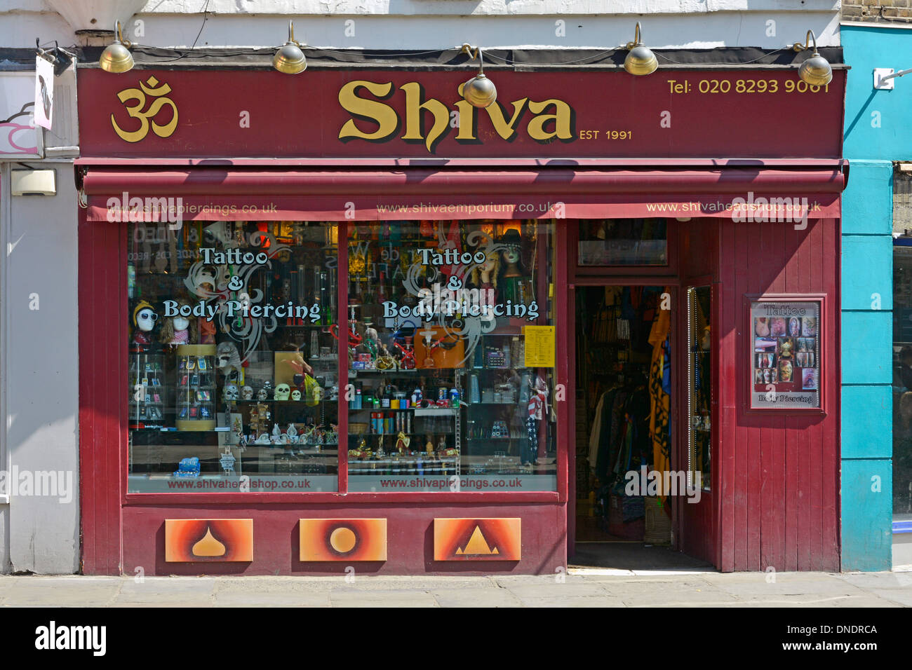 Shiva segno sopra tatuaggio salotto e corpo piercing business shop vetrina e ingresso Greenwich Londra Inghilterra Regno Unito Foto Stock