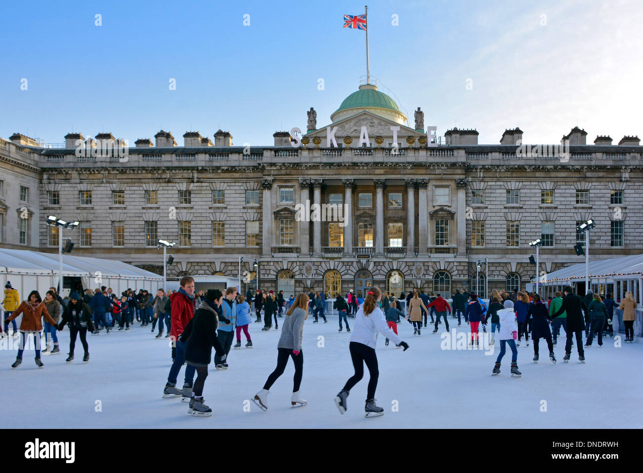 Adulti e bambini pattinatori di ghiaccio con sfondo storico Somerset House Edificio e cortile sulla temporanea pista di pattinaggio invernale Strand Londra Inghilterra Regno Unito Foto Stock