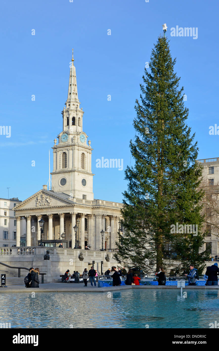 Albero di Natale in abete rosso norvegese in omaggio dalla Norvegia a Trafalgar Square, chiesa di St Martin in the Fields e guglia cielo blu inverno giorno Londra Inghilterra Regno Unito Foto Stock