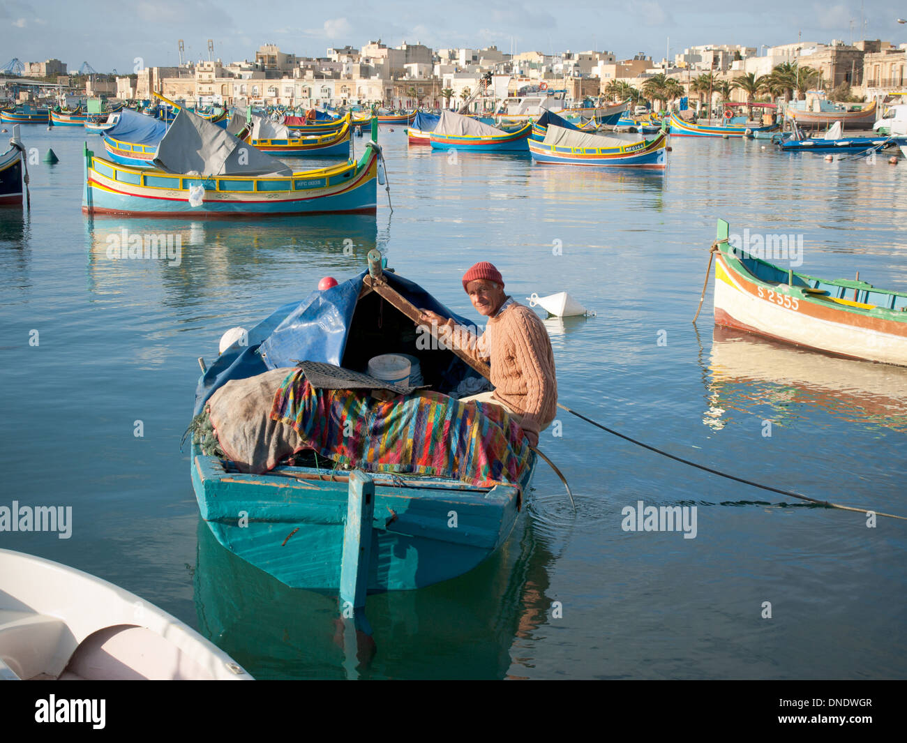 Un locale, Pescatore maltese in un colorato luzzu tradizionale barca da pesca nel porto di Marsaxlokk di Marsaxlokk, Malta. Foto Stock