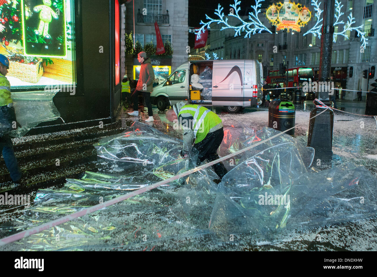 Londra, Regno Unito. 23 Dic, 2013. Giant snow globe intorno a Eros in Piccadilly Circus a Londra si sgonfia a causa del forte vento. Il maltempo ha provocato interruzioni in tutto il Regno Unito. Credito: martyn wheatley/Alamy Live News Foto Stock