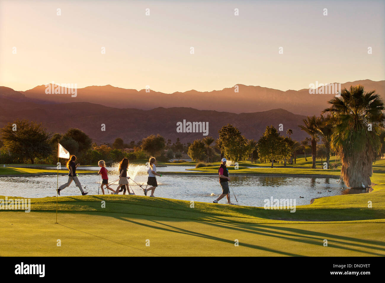 I bambini piccoli energeticamente seguire il loro tutor di golf per una lezione al primo tee facility in Palm Desert, CA, Stati Uniti d'America Foto Stock