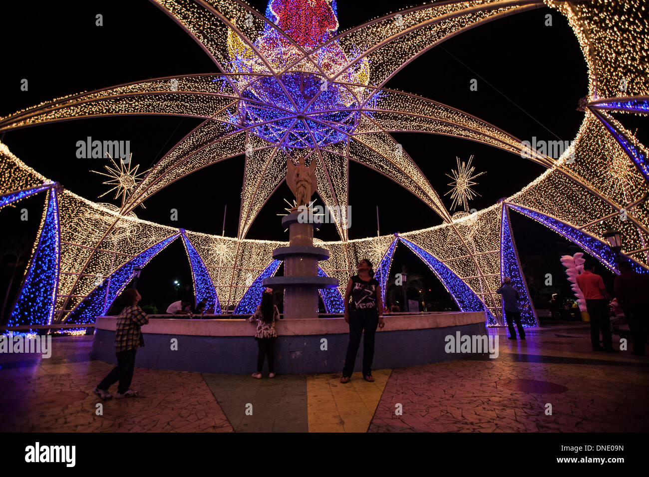 Maracaibo, Venezuela. 23 Dic, 2013. Residenti a piedi su un quadrato decorato con le luci di natale nella città di Maracaibo, Stato Zulia, Venezuela, a Dic. 23, 2013. Credito: Boris Vergara/Xinhua/Alamy Live News Foto Stock