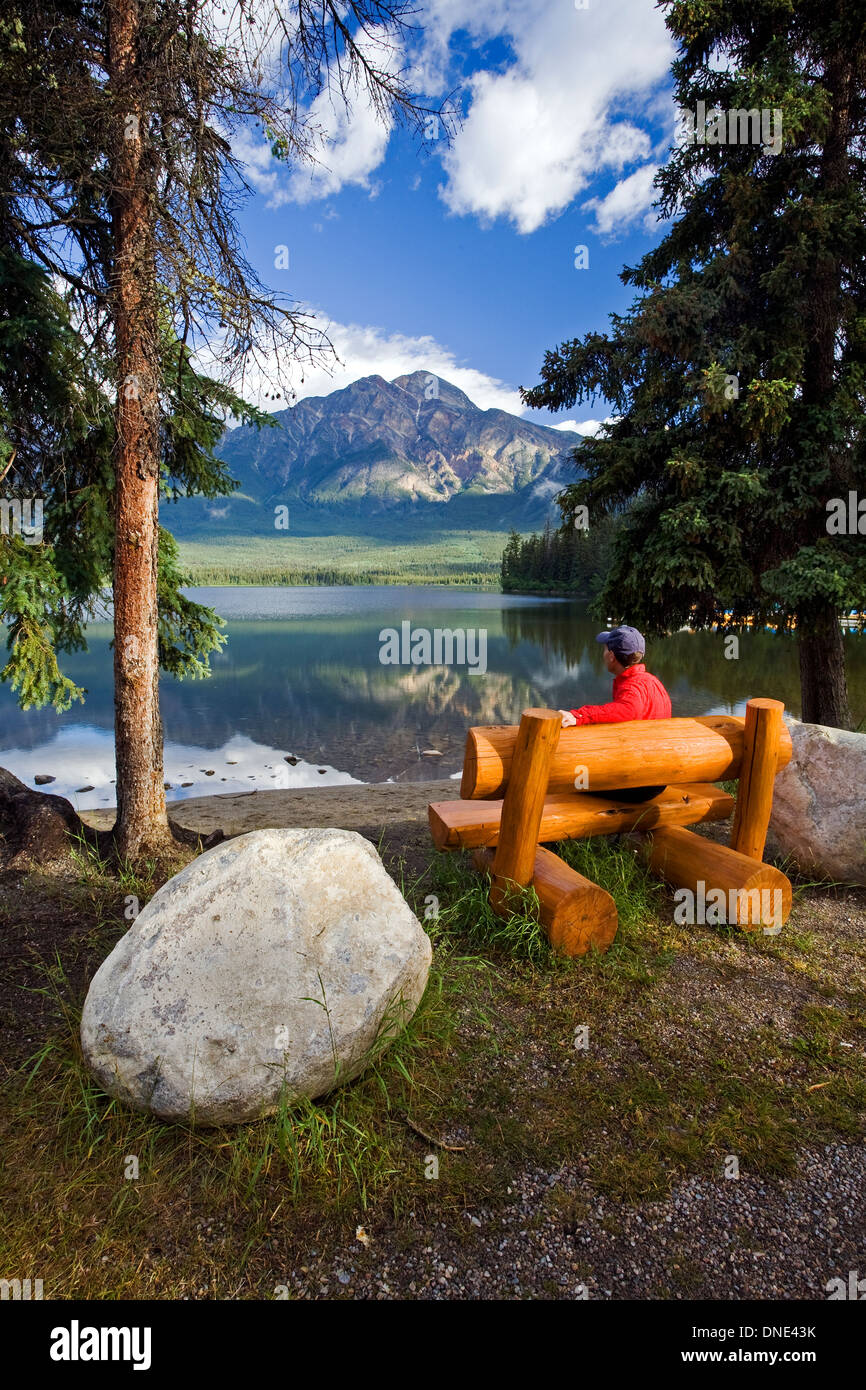 Metà maschio età seduta sul banco a Lago Piramide guardando a piramide, di montagna del Parco Nazionale di Jasper, Alberta, Canada. Foto Stock