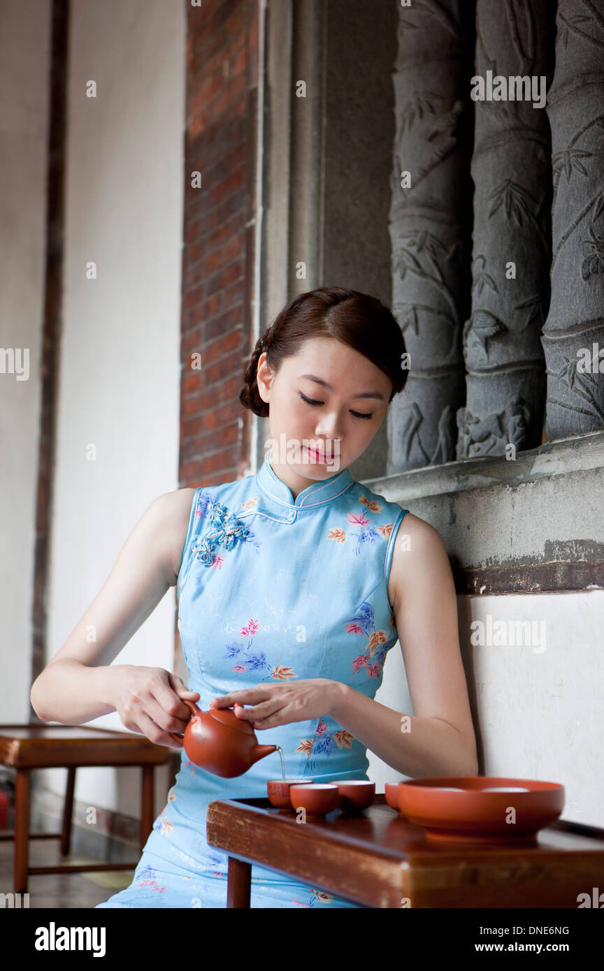 Giovane donna indossa cheongsam e teiera in azienda Foto Stock