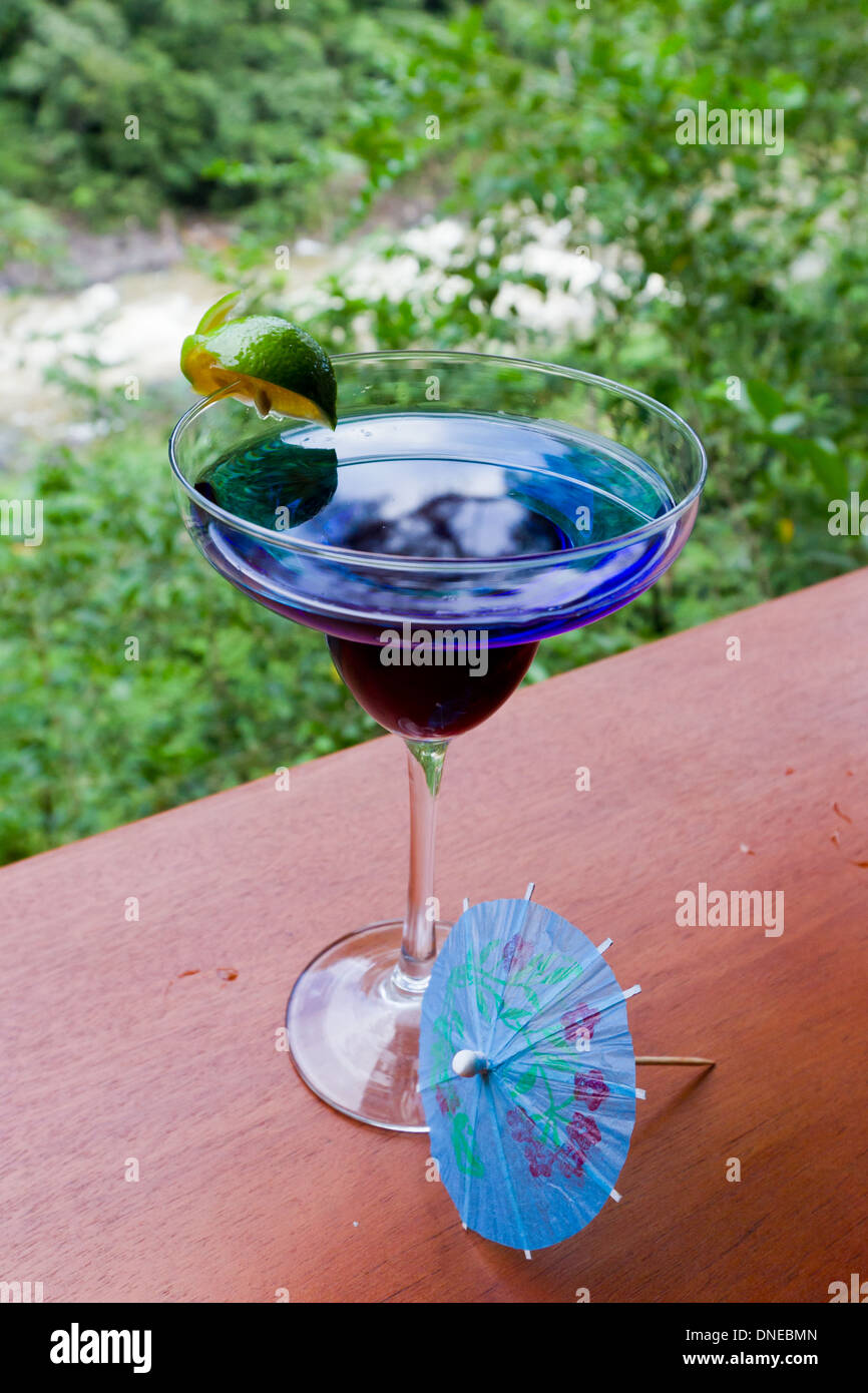 Blue rain forest drink servito su un listello di legno con la giungla in background Foto Stock