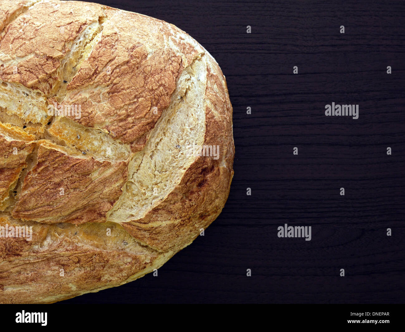 Filone di pane cotto domestico in legno marrone scuro e colpo di superficie da sopra Foto Stock