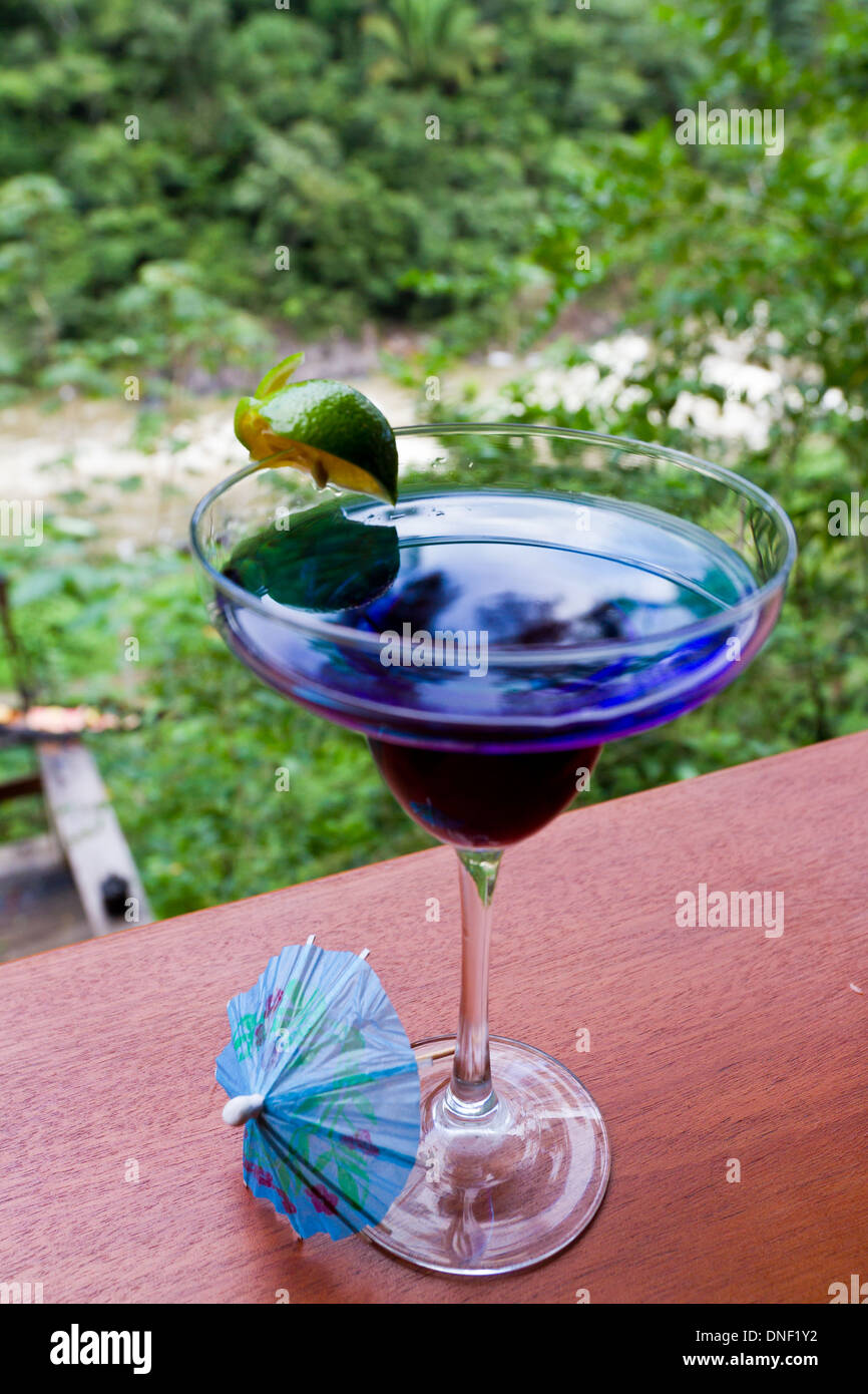 Blue rain forest drink servito su un listello di legno con la giungla in background Foto Stock