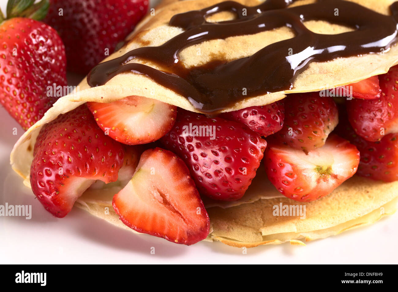 Crêpe riempito con fragole fresche e salsa al cioccolato sulla parte superiore Foto Stock