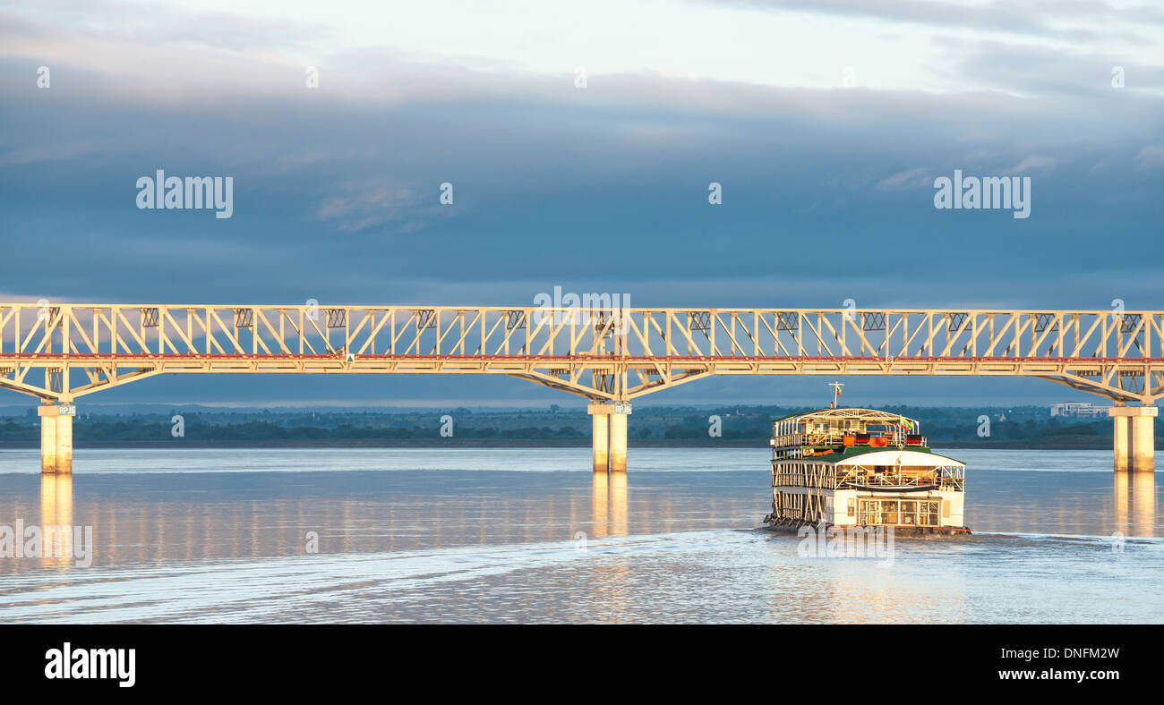 Imbarcazione turistica si avvicina alla Pakokku ponte che attraversa il fiume Irrawaddy in Myanmar. Myanmar viaggi e immagini di persone. Foto Stock