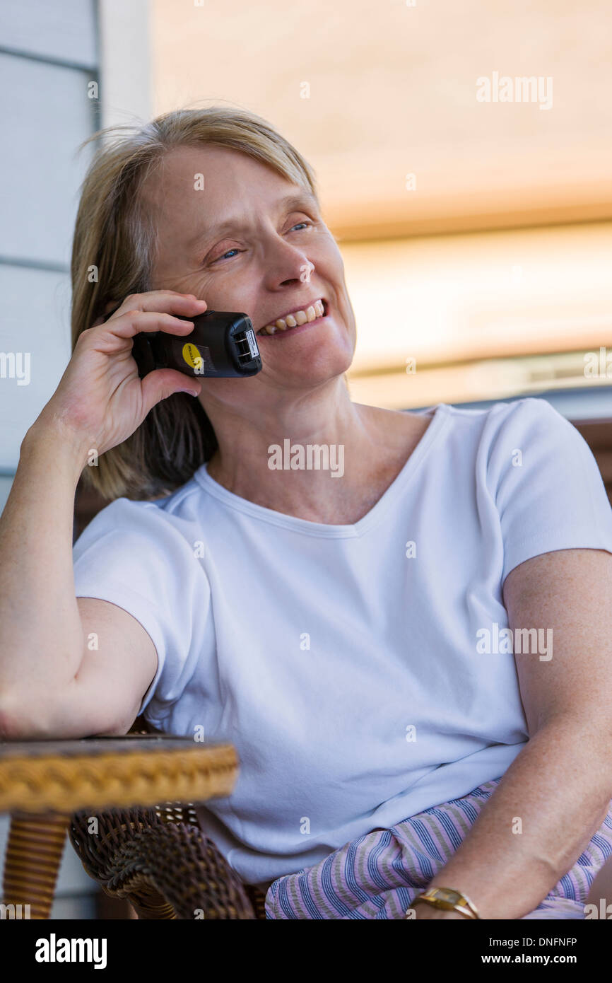 Donna di mezza età al di fuori, sorridente, parlare su un telefono wireless Foto Stock