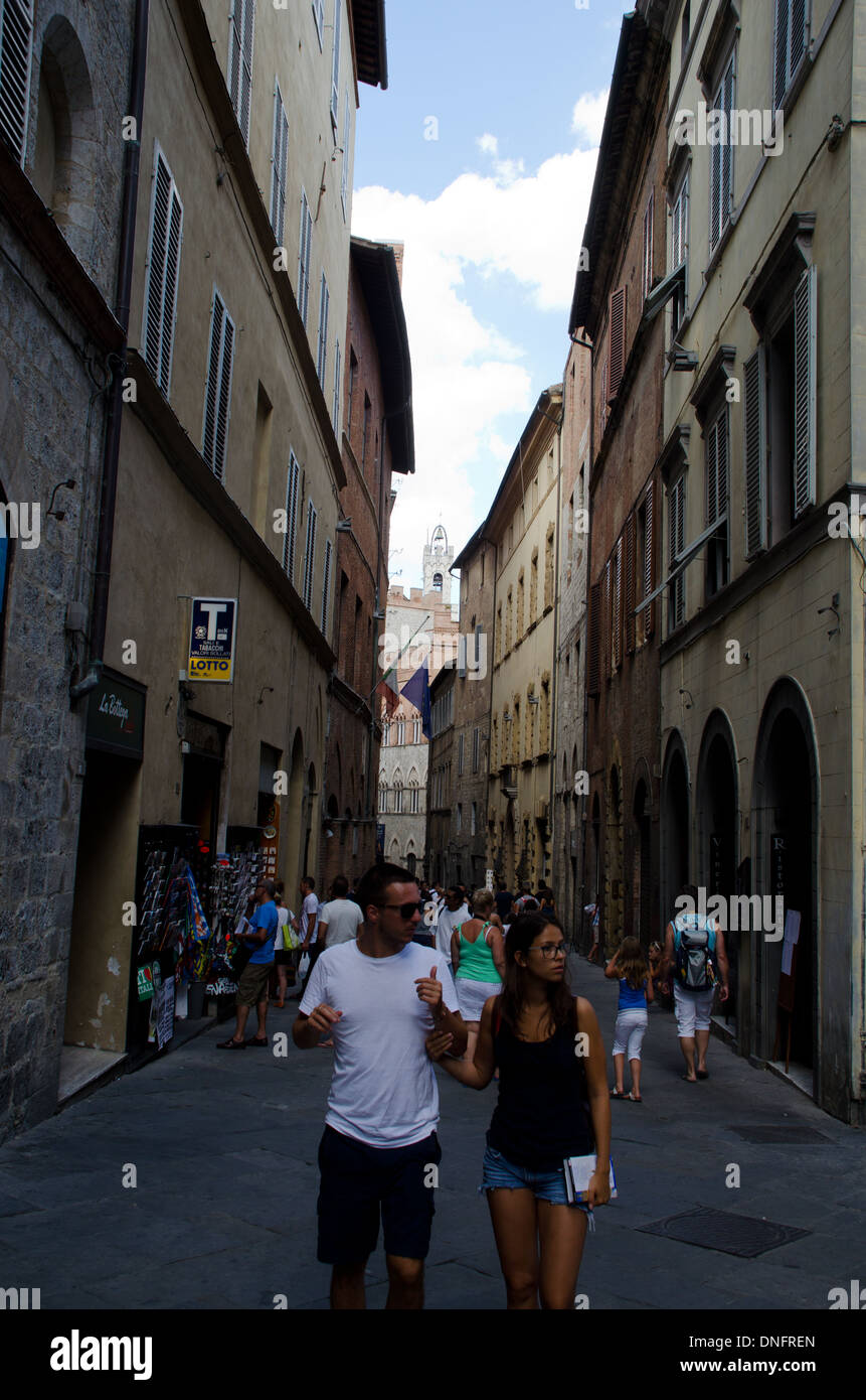 L uomo e la donna scendendo nelle strade strette a Siena, Toscana, Italia. Foto Stock