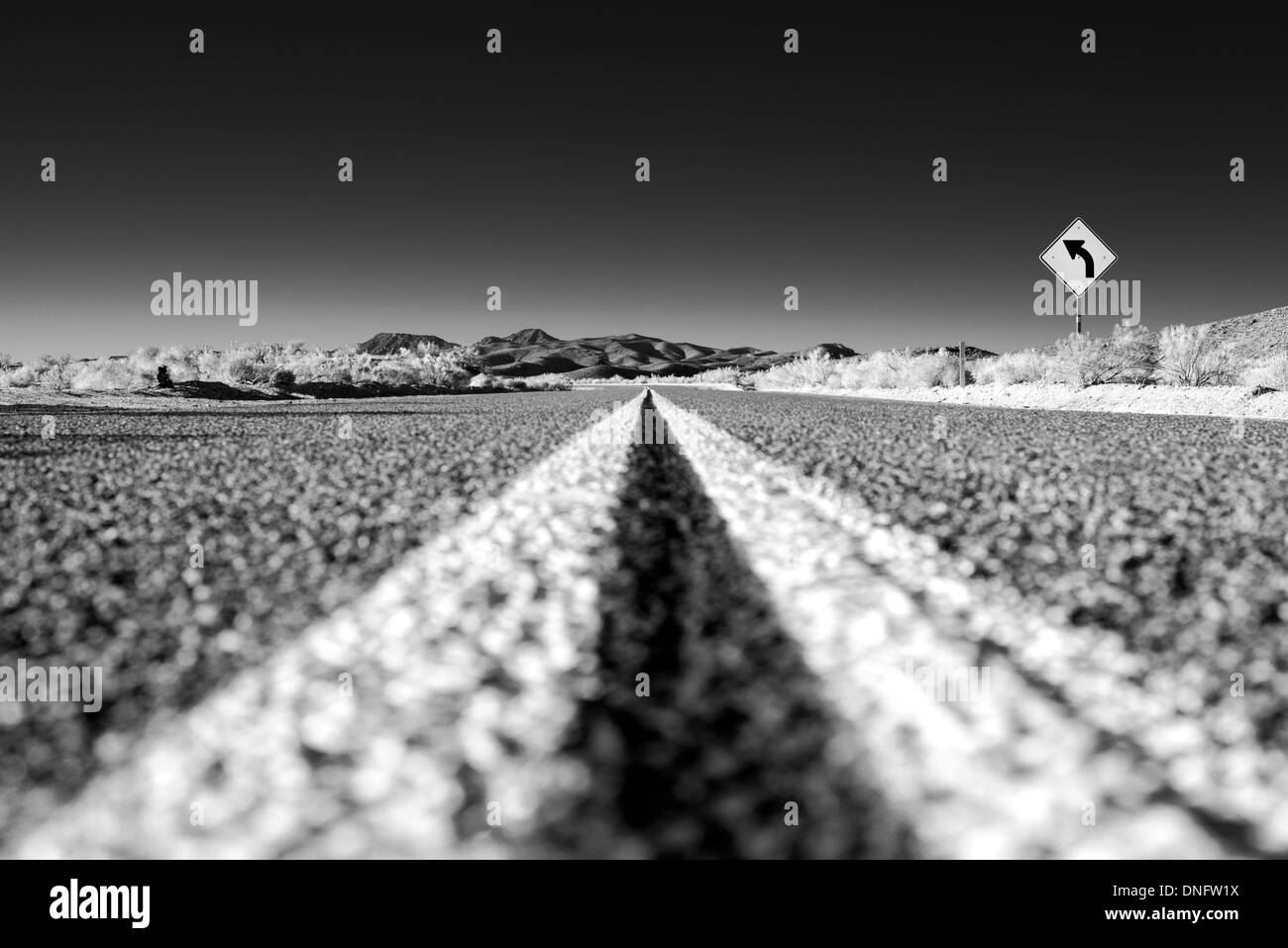 Strada nel deserto e girare il segno Foto Stock