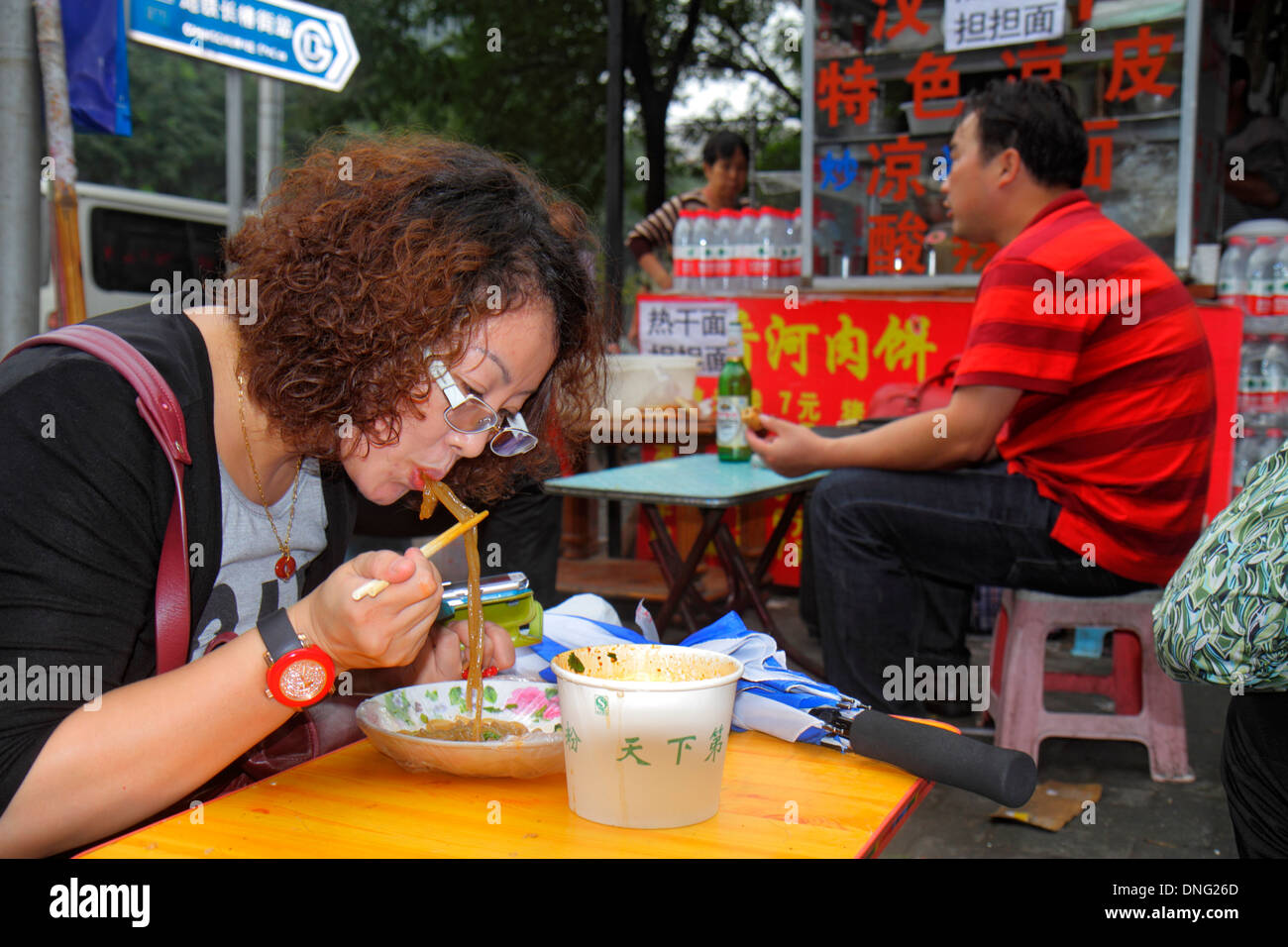 Pechino Cina, Asia, cinese, orientale, Xicheng, asiatici, adulti, donne donna donna donna donna donna donna donna donna donna donna donna donna donna, mangiare, utilizzando bacchette, tagliatelle, marciapiede, ristorante resto Foto Stock