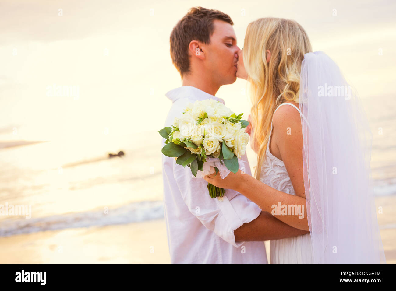 Appena una coppia sposata baciare sulla spiaggia tropicale, Hawaii matrimonio sulla spiaggia Foto Stock