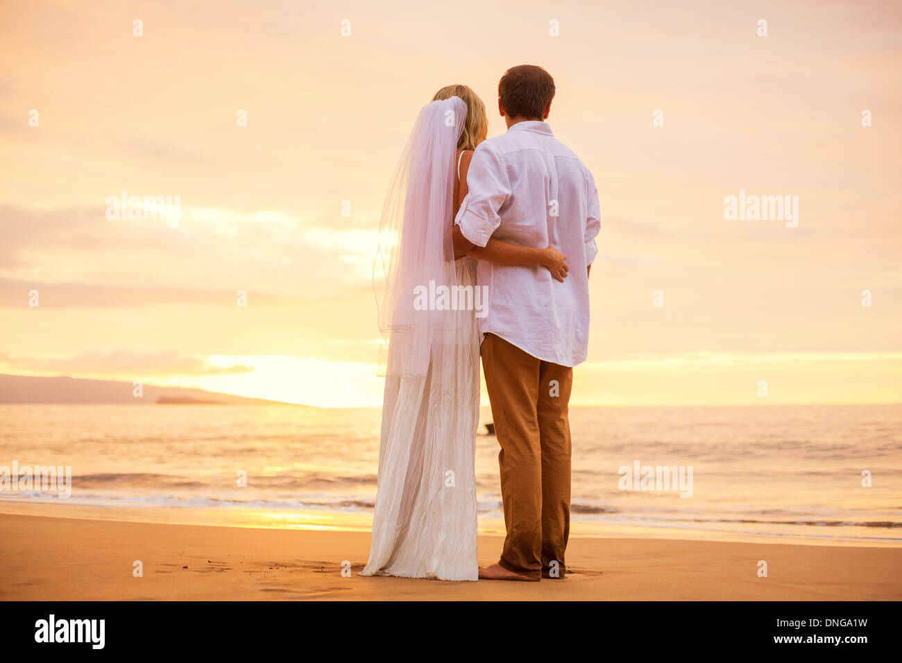 Appena una coppia sposata sulla spiaggia tropicale al tramonto, Hawaii matrimonio sulla spiaggia Foto Stock