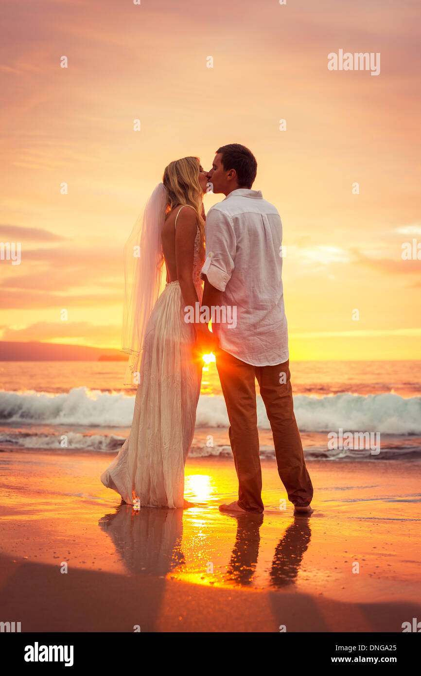 Appena una coppia sposata baciare sulla spiaggia tropicale al tramonto, Hawaii matrimonio sulla spiaggia, intimo momento amoroso Foto Stock