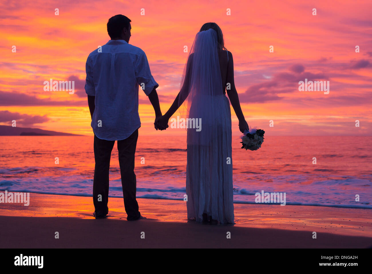 Appena una coppia sposata tenendo le mani sulla spiaggia al tramonto, Hawaii matrimonio sulla spiaggia Foto Stock