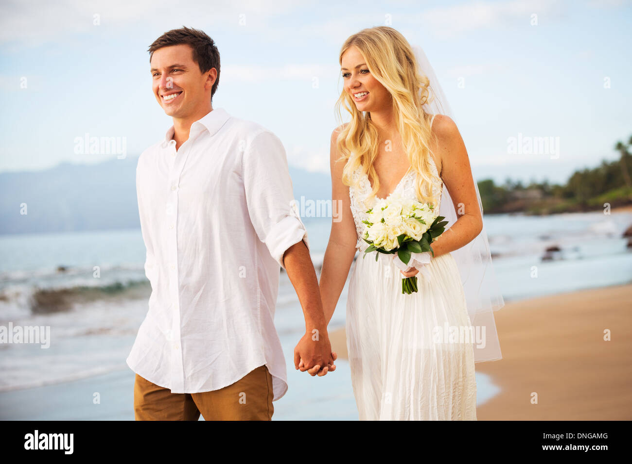 Appena una coppia sposata a piedi sulla spiaggia al tramonto, Hawaii matrimonio sulla spiaggia Foto Stock