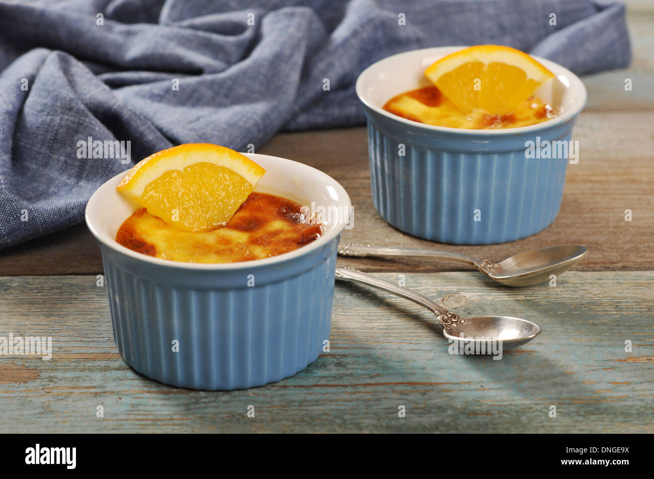 Le creme brulee in ceramica stampo da forno con arancia sul tavolo di legno Foto Stock