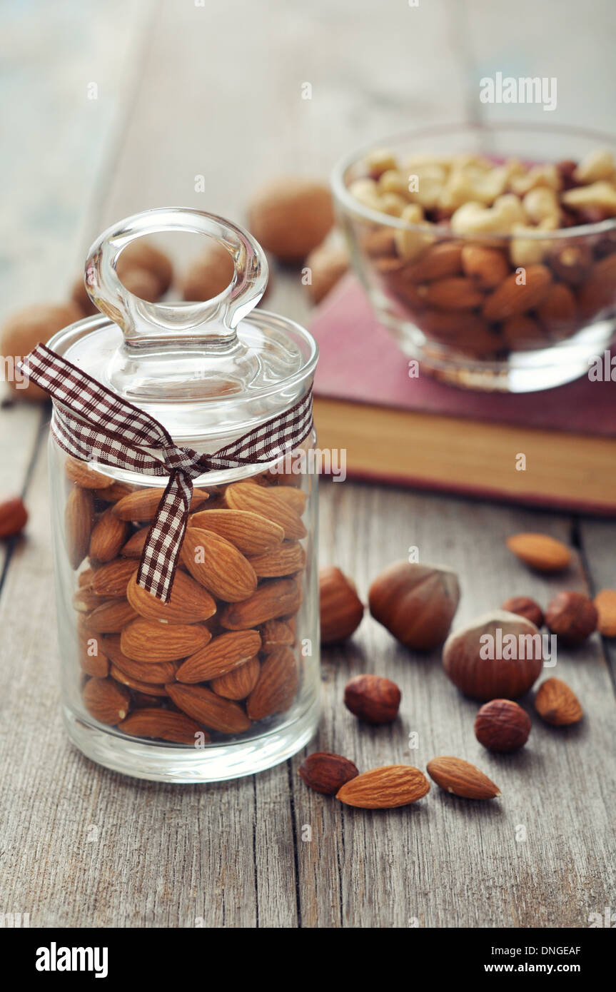 Mandorle in un barattolo di vetro con il dado mix su sfondo di legno Foto Stock