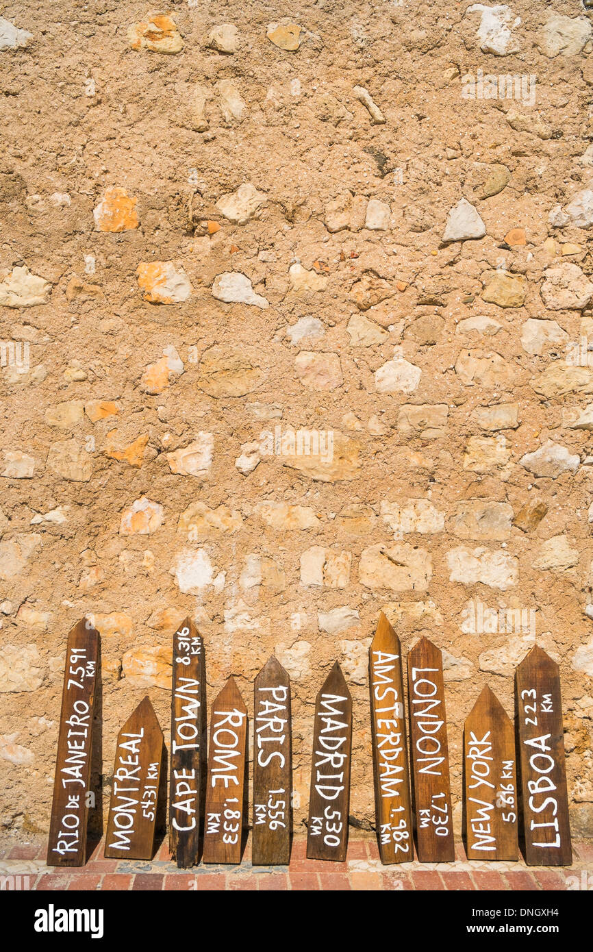 Dipinta di fresco indicatori di distanza appoggiato su di un muro di pietra naturale, Faro, Algarve, PORTOGALLO Foto Stock