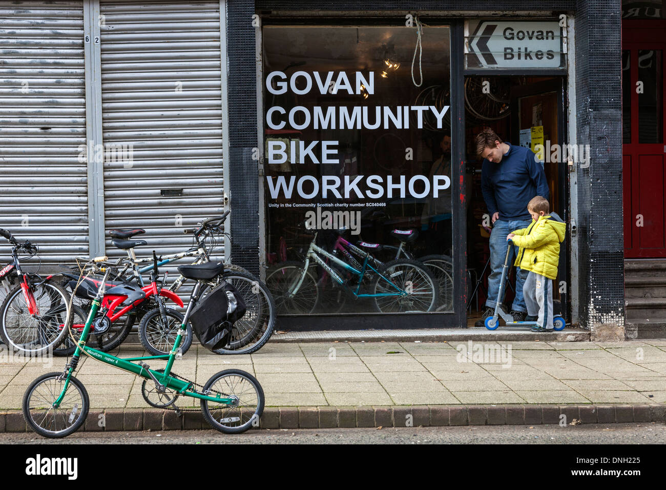 Ragazzo giovane chiedendo consigli circa il suo scooter giocattolo da un uomo in un negozio di biciclette, Govan, Glasgow, Scotland, Regno Unito Foto Stock