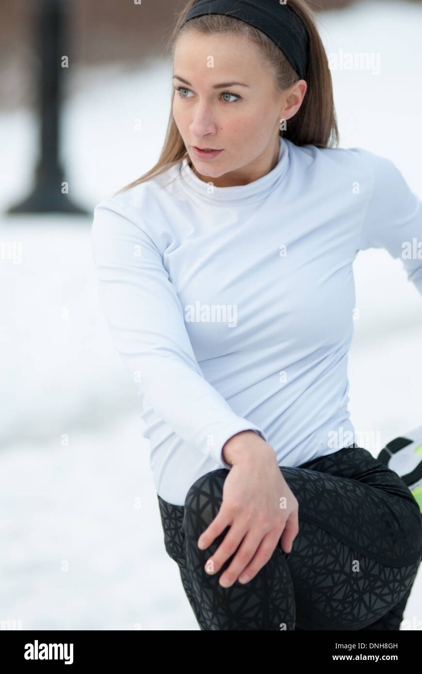 Una bella donna si estende prima di correre in una fredda giornata invernale Foto Stock