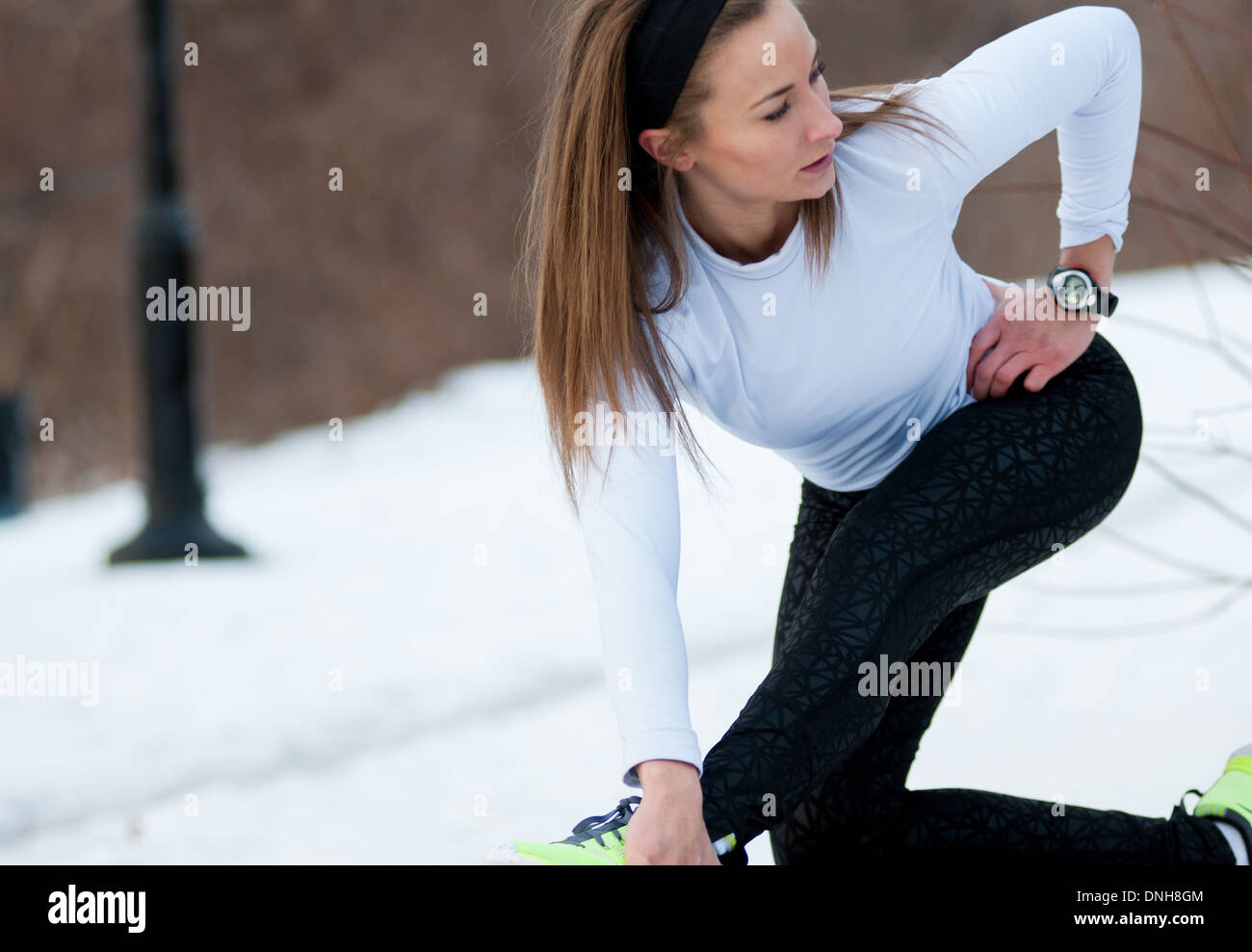 Una femmina di runner si estende prima di correre in una fredda giornata invernale. Foto Stock