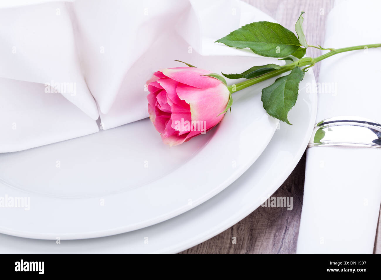 Romantico elegante formale messa in tavola con una sola rosa rosa e nastro decorativo per un innamorato il giorno di San Valentino Foto Stock
