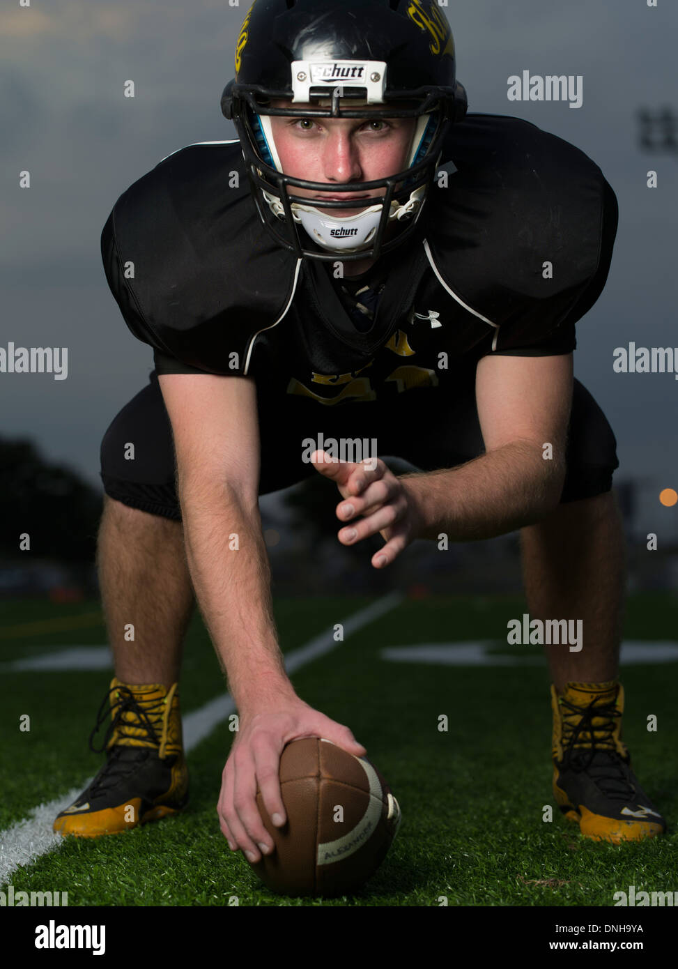 American High School giocatore di football in uniforme con il casco e il calcio. Foto Stock