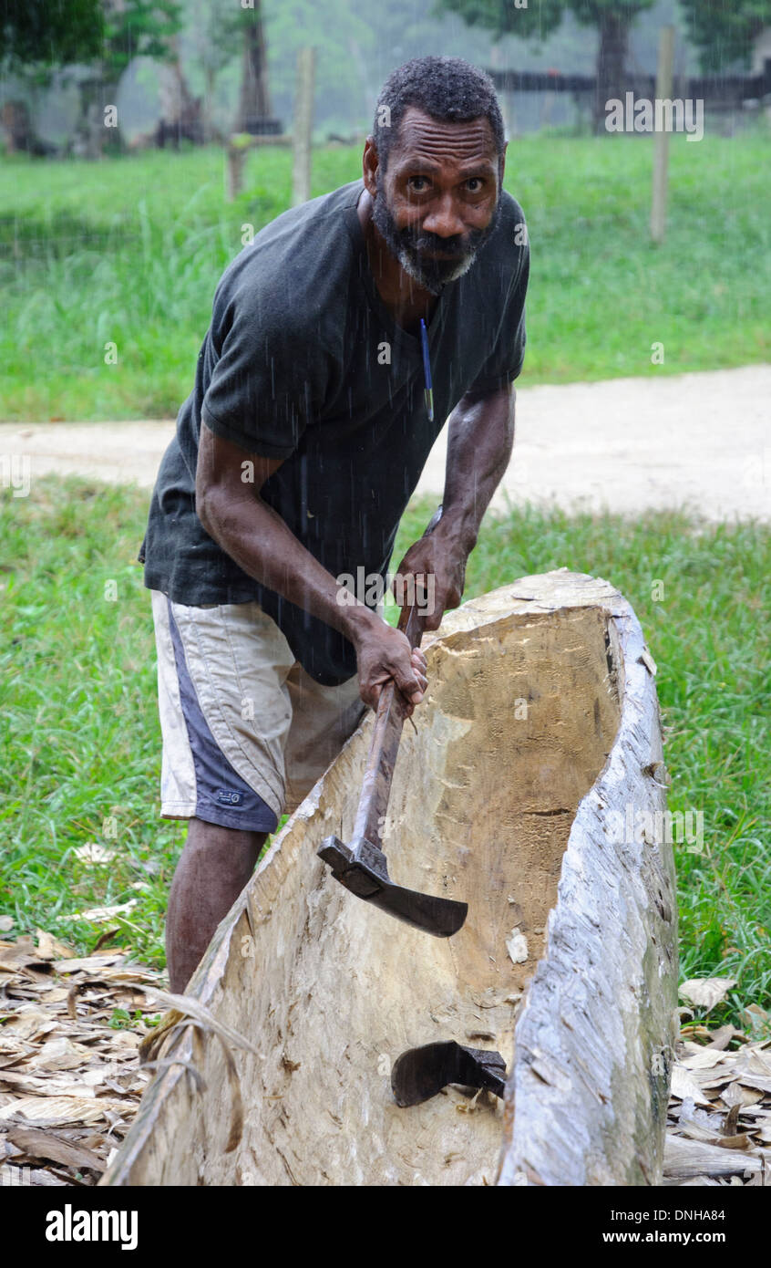 L'uomo facendo una piroga con un'ascia, nel modo tradizionale. Foto Stock
