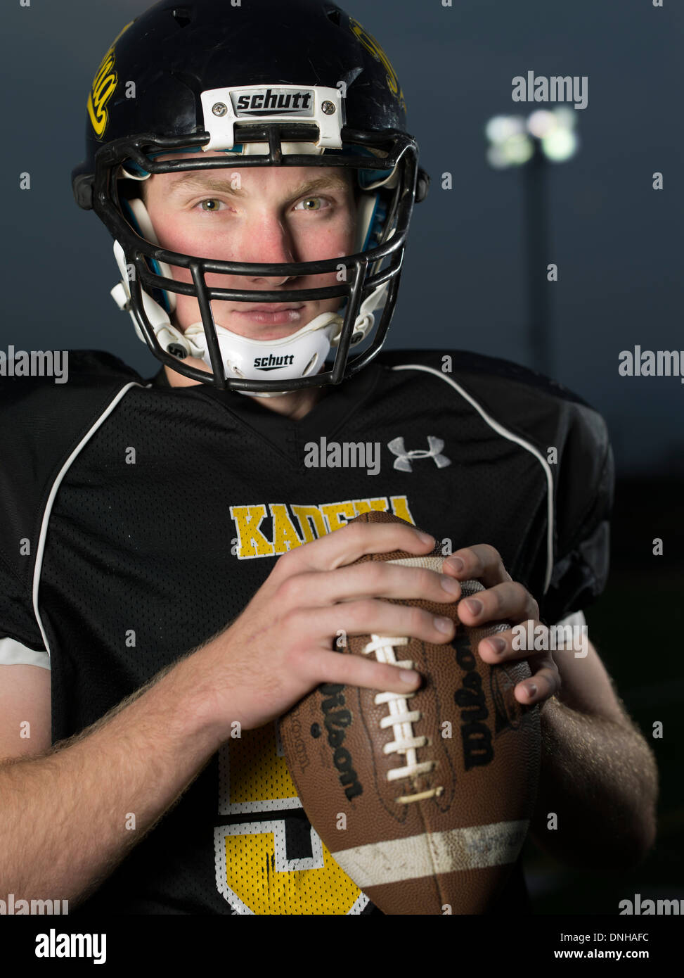American High School giocatore di football in uniforme con il casco e il calcio. Foto Stock