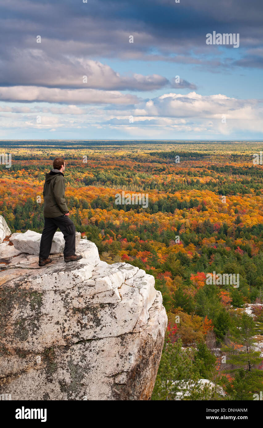 Un escursionista sorge in corrispondenza di un bordo di una scogliera ammirando la vista a Killarney Provincial Park, Ontario, Canada. Foto Stock