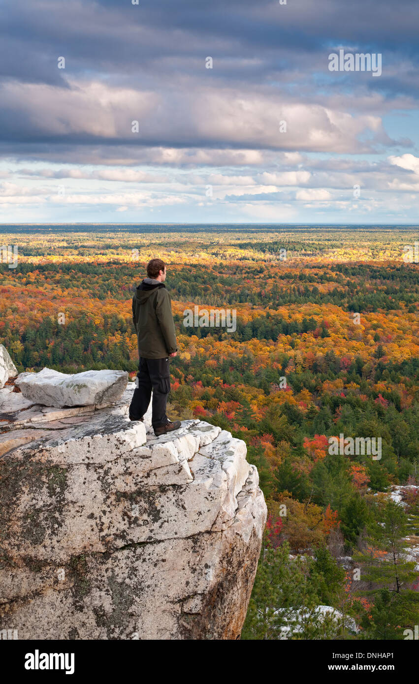 Un escursionista sorge in corrispondenza di un bordo di una scogliera ammirando la vista a Killarney Provincial Park, Ontario, Canada. Foto Stock