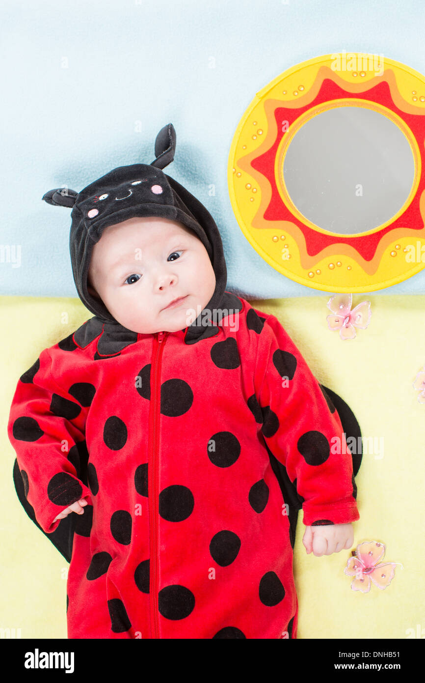 Graziosa bambina vestito in costume coccinella su sfondo verde. Il concetto di infanzia e vacanze Foto Stock