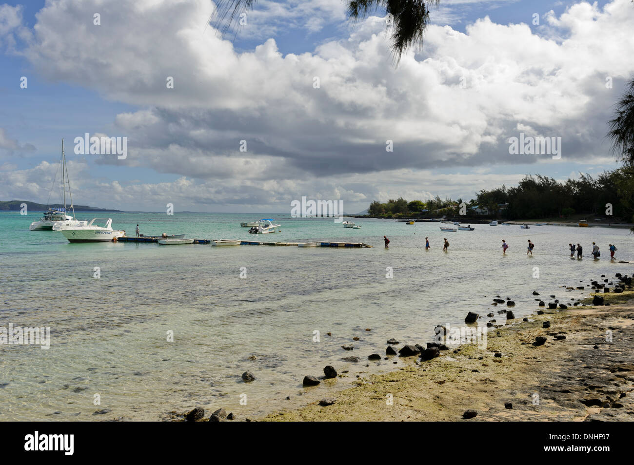 I turisti a piedi nel mare poco profondo a riva per arrivare su una barca veloce, Mauritius. Foto Stock