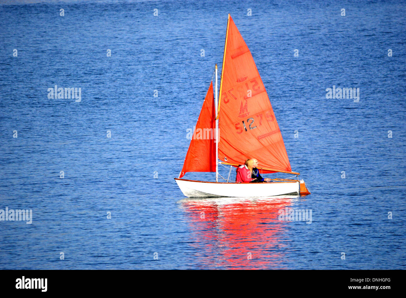 Di colore rosso o arancione set vele contro un mare di un blu intenso Foto Stock