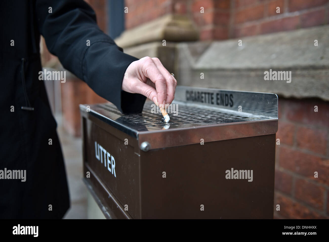 Una persona urto fuori una sigaretta su una lettiera bin Foto Stock