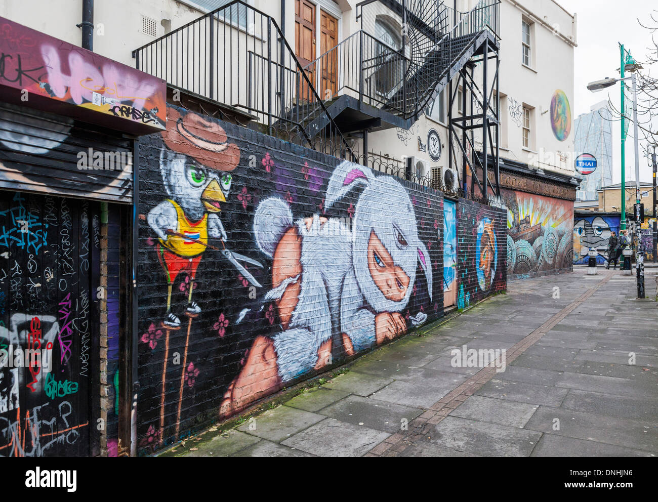 Arte di strada da Alex faccia. Un uccello nel cappello e maglietta gialla taglia le pellicce di tre eyed baby in bunny suit con cesoia, Pedley Str., Londra Foto Stock