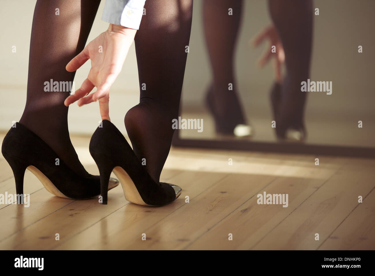 Primo piano di una giovane donna gambe indossando tacco alto scarpe nella parte anteriore dello specchio a casa. Giovani femmine di vestirsi in ambienti chiusi. Foto Stock